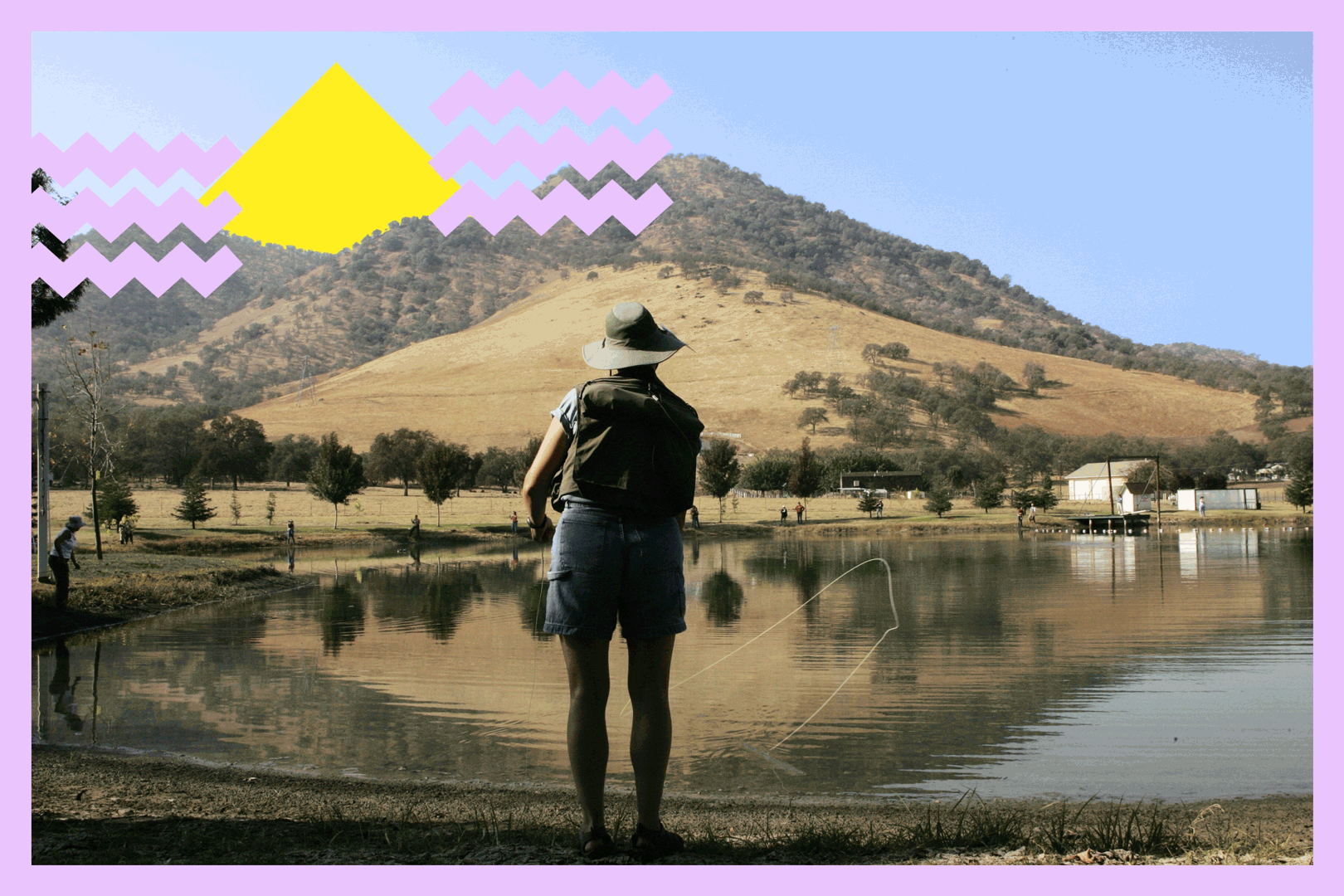A person in silhouette fly-fishing with a body of water in front of them and a hillside in the distance
