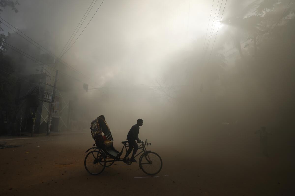 A rickshaw puller rides through thick smoke.