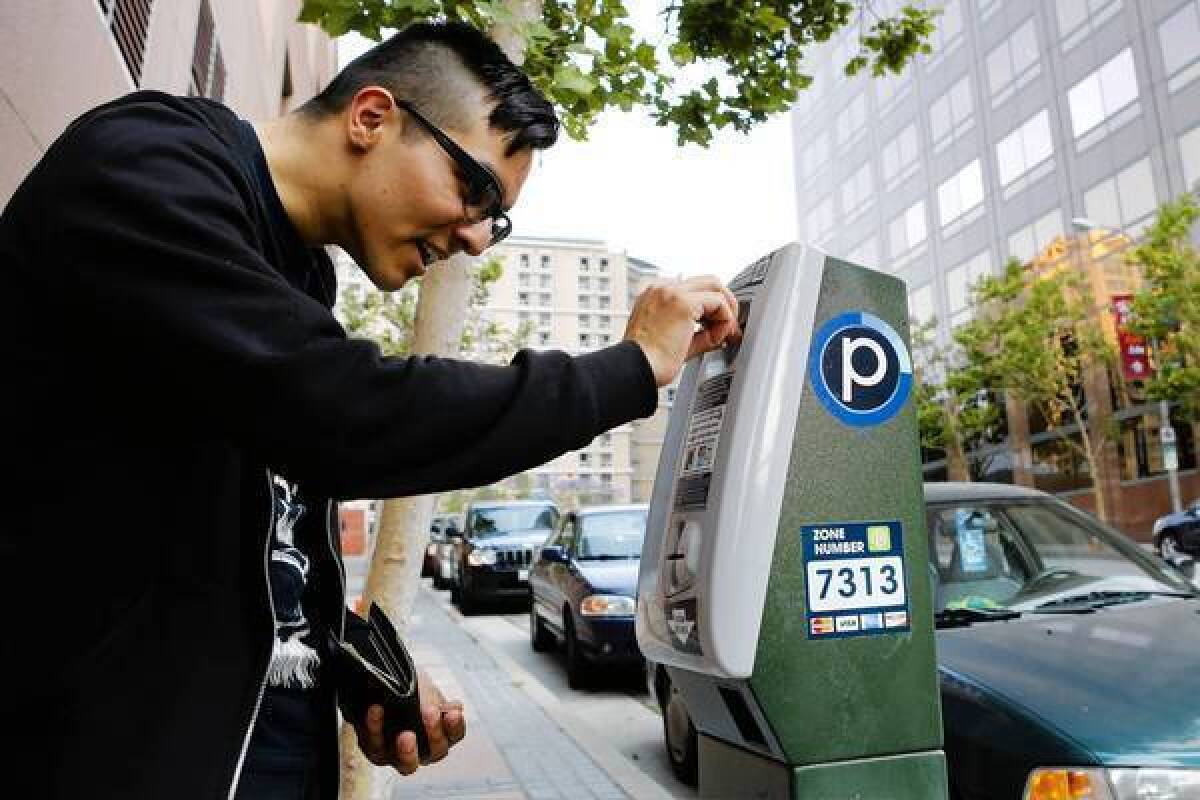 Ross Cuevas of Westwood puts coins in a parking meter at 3rd Street and Grand Avenue in downtown Los Angeles.