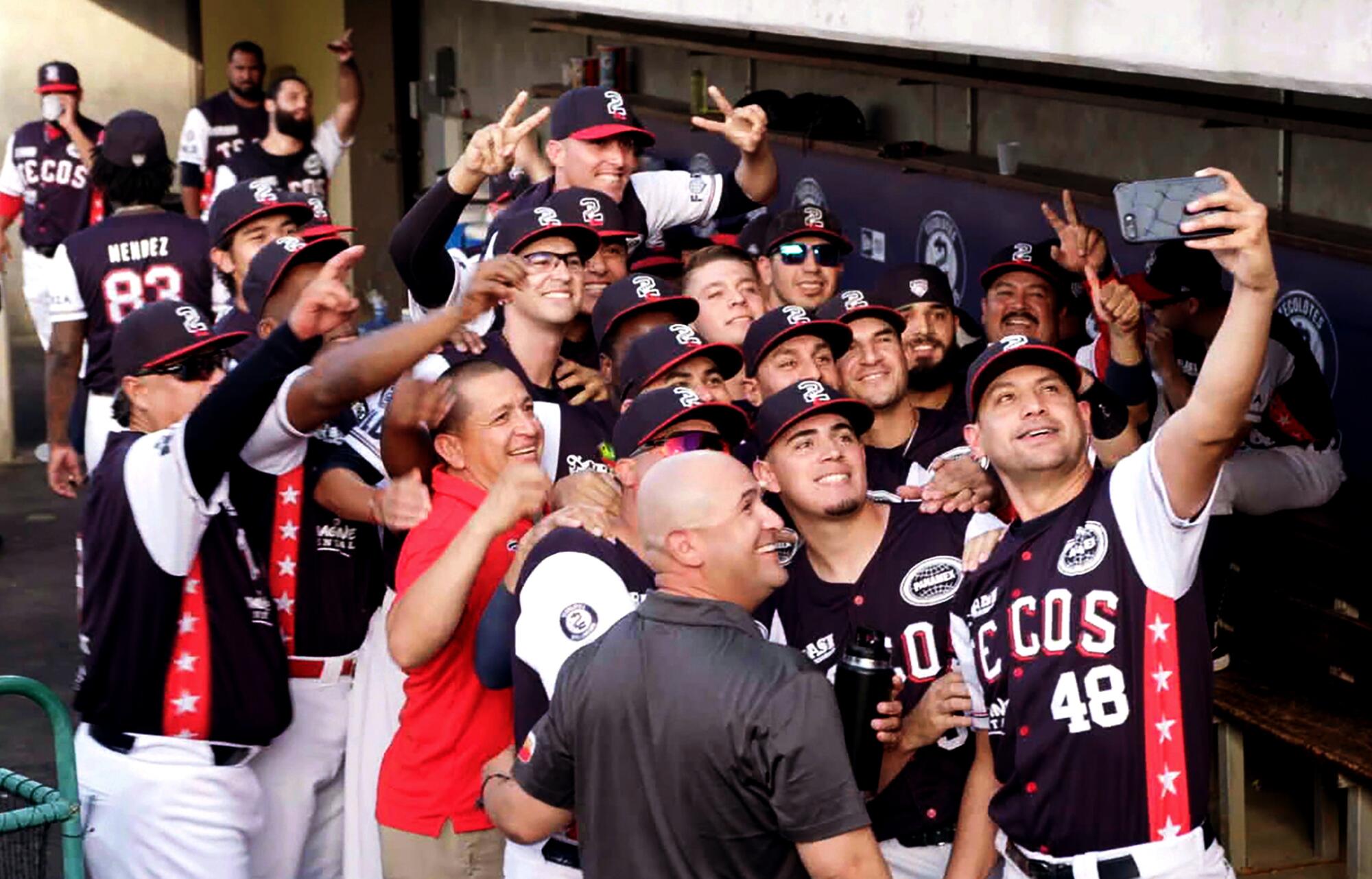 Los Tecolotes, a binational baseball team, takes a selfie in the dugout.
