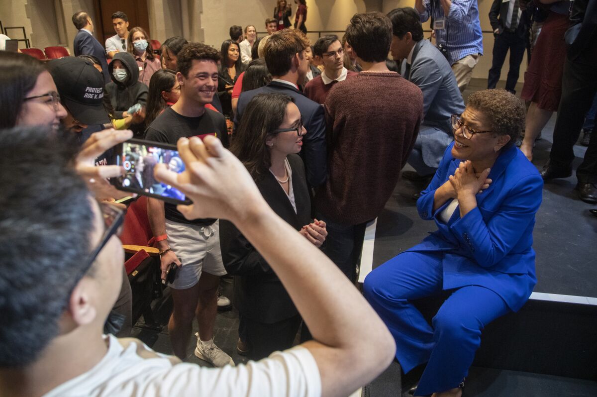 Rep. Karen Bass, seated and wearing a blue outfit, talks with a group of young people
