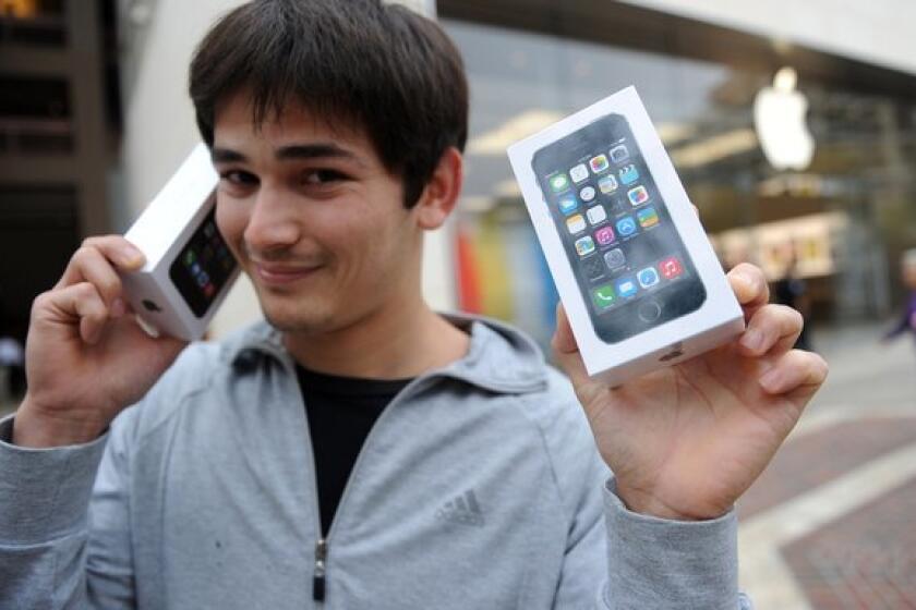 Kerim Muhammet poses with two new Apple iPhone 5S devices after waiting in line overnight to be among the first to purchase the smartphones at the Americana at Brand shopping complex in Glendale, Calif.