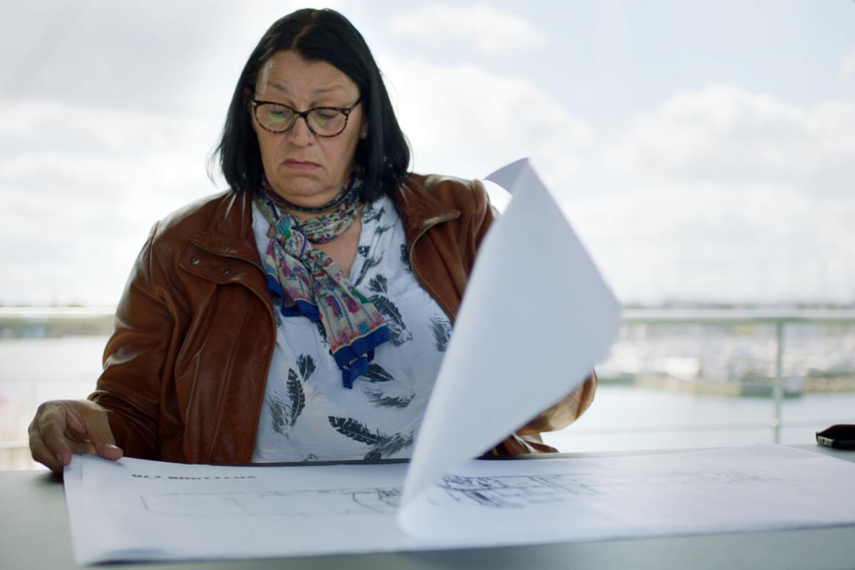 A woman with glasses looks at blueprints.