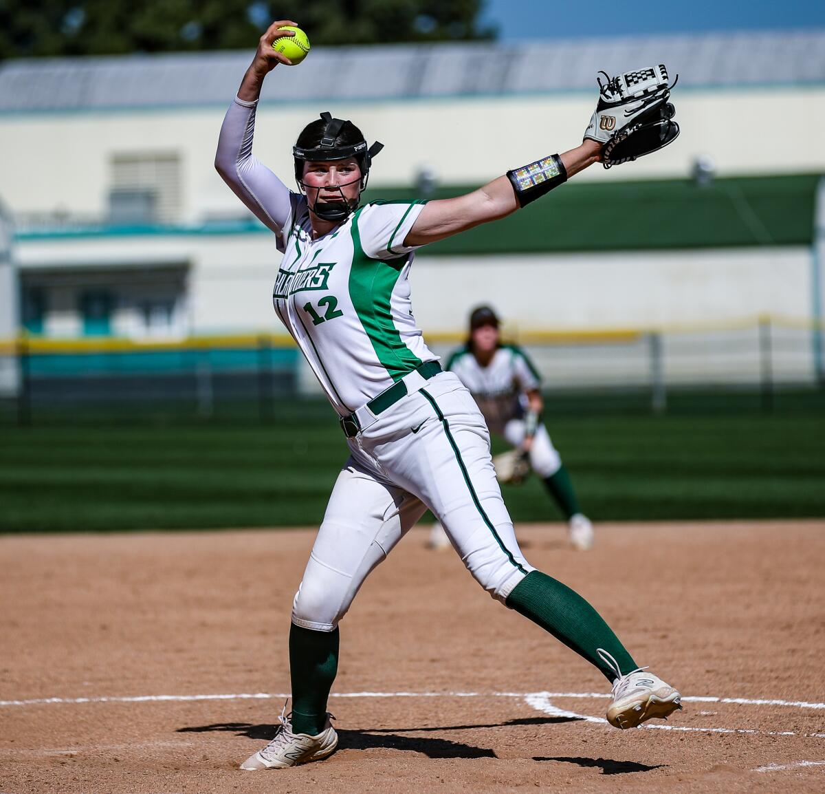 Right-hander Addison Moorman wearing a Granada Hills uniform and face guard as she winds up in the pitching circle