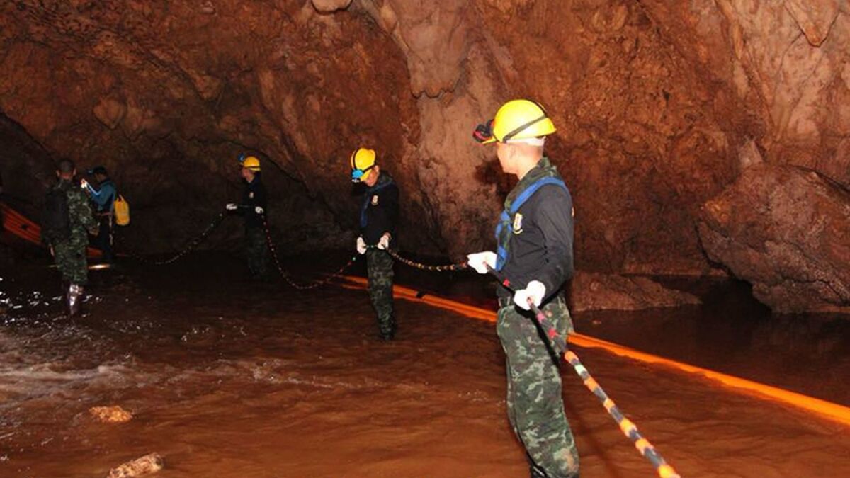 Thai military personnel carrying equipment inside a cave complex