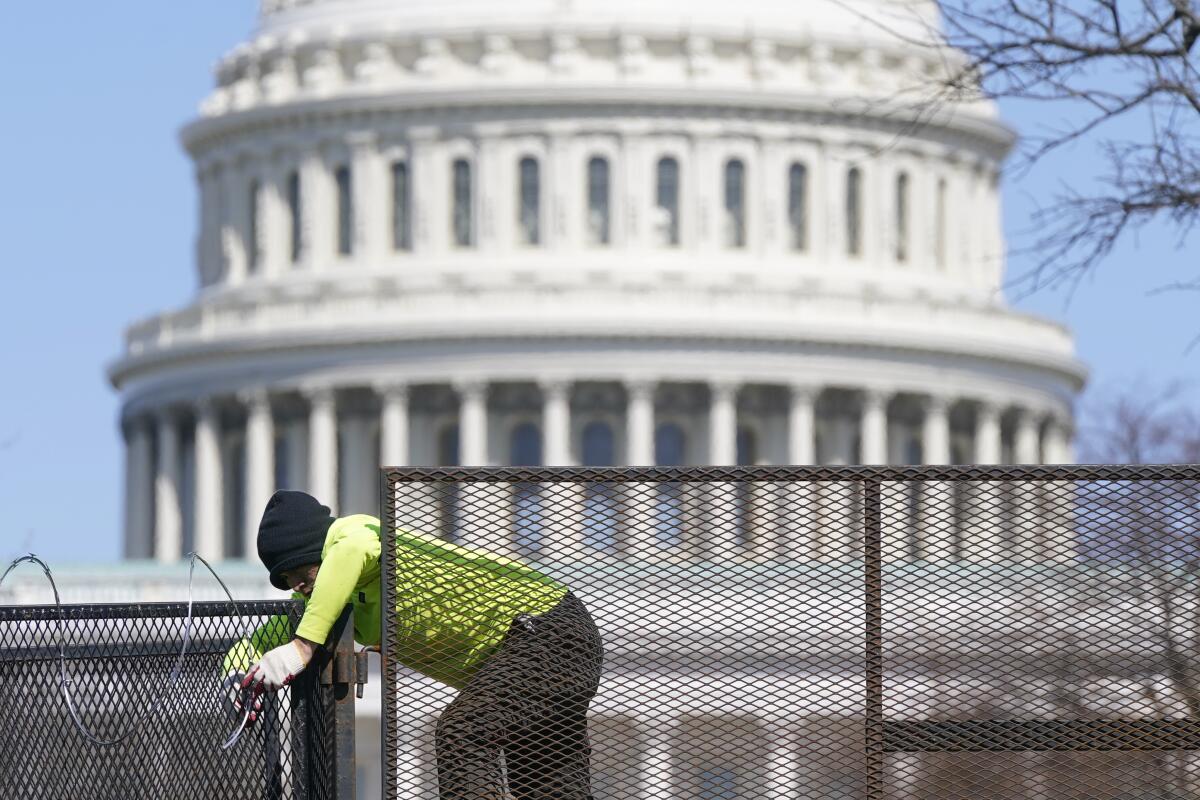 Worker removing razor wire from fence on Capitol Hill