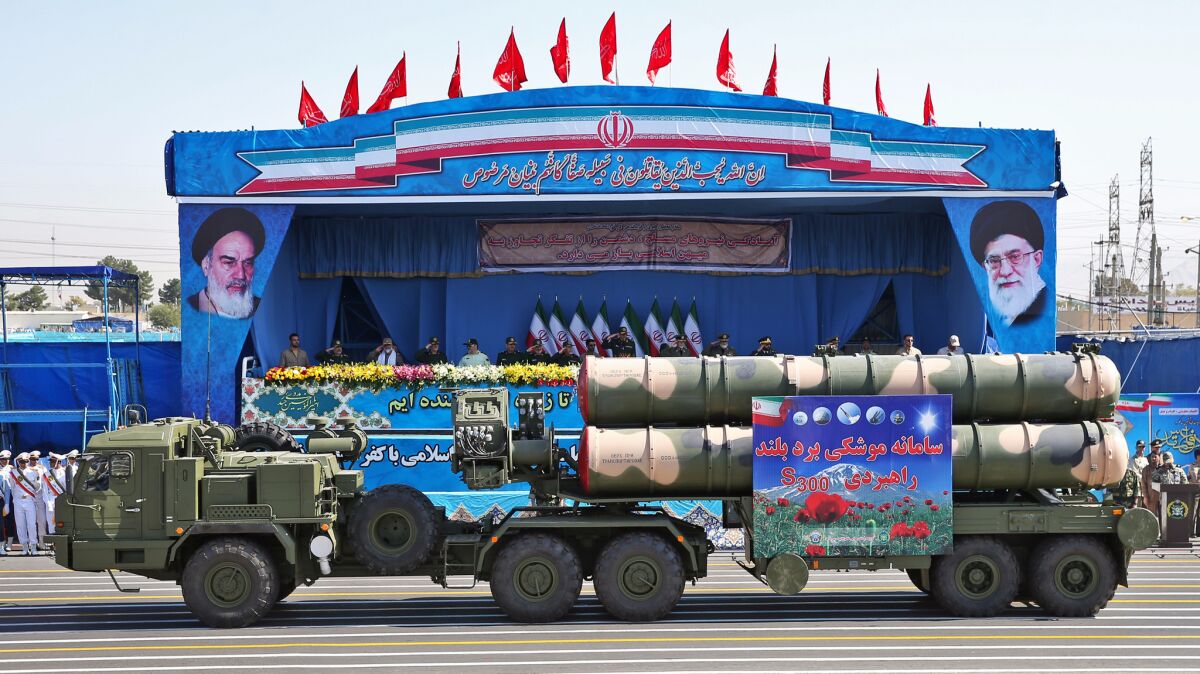 In front of portraits of supreme leader Ayatollah Ali Khamenei, right, and late revolutionary founder Ayatollah Khomeini, a long-range missile system is displayed by Iran's army during a military parade held just outside Tehran on Sept. 21.