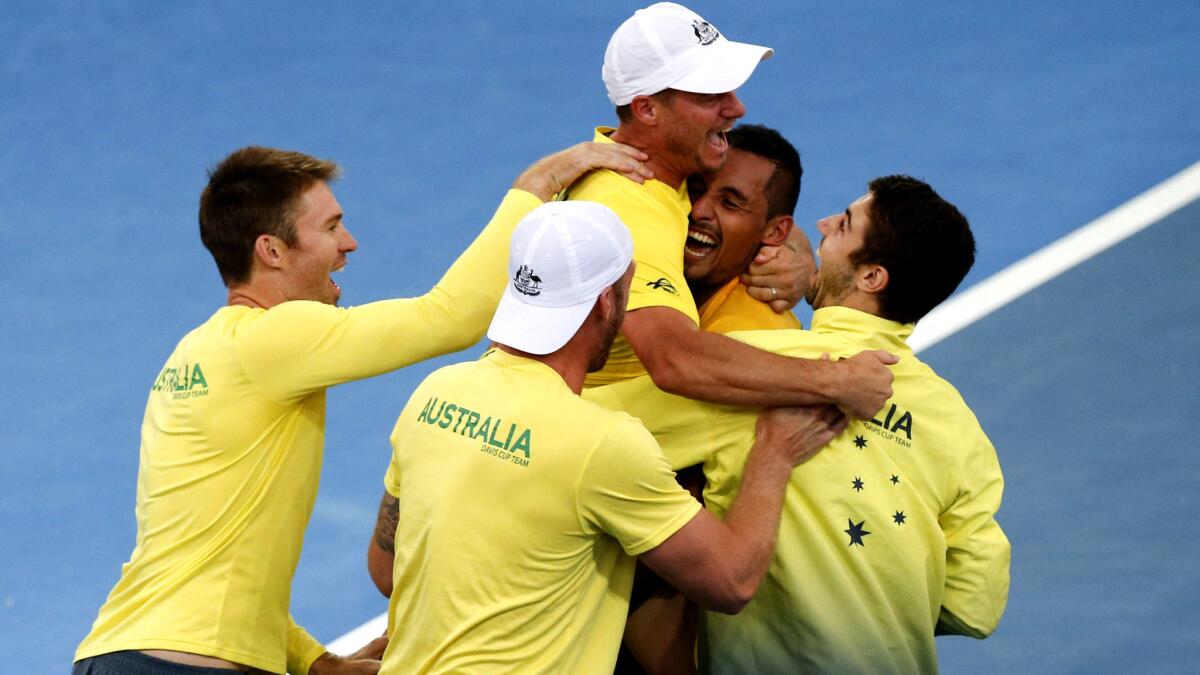 Australian teammates engulf Nick Kyrgios (second from right) after he clinched the Davis Cup win on Sunday.
