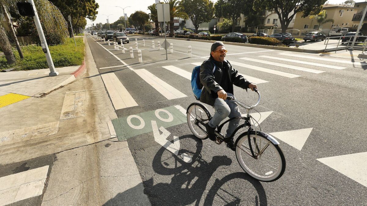 A bicyclist rides along Venice Boulevard in West Los Angeles in March. The curbside lane is marked by plastic pylons buffered by parked cars and has ignited controversy on the Westside.