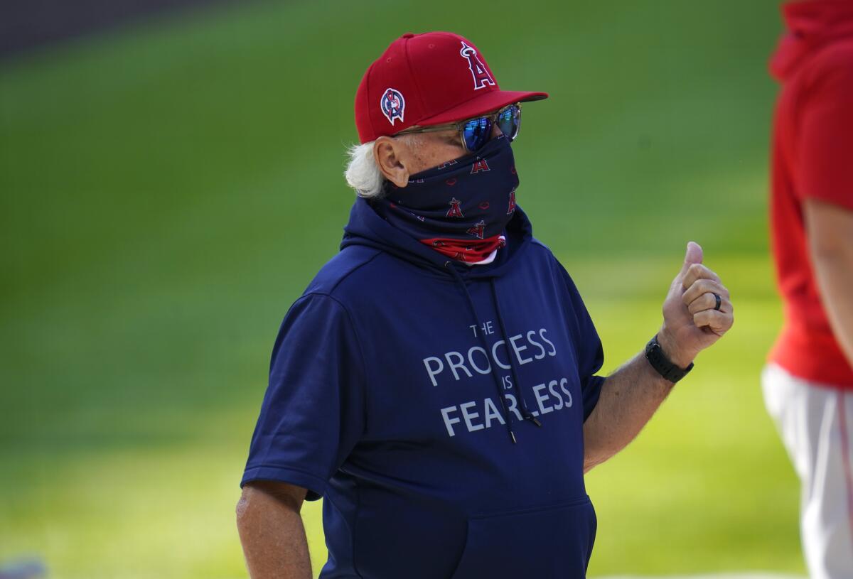 Angels manager Joe Maddon confers with a player as he warms up before a game against Colorado on Sept. 12, 2020, in Denver.