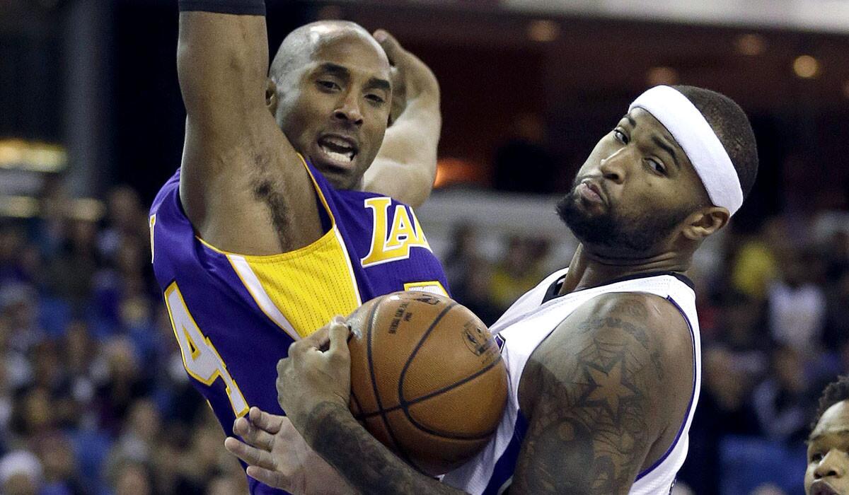Kings center DeMarcus Cousins pulls down a rebound next to Lakers guard Kobe Bryant.