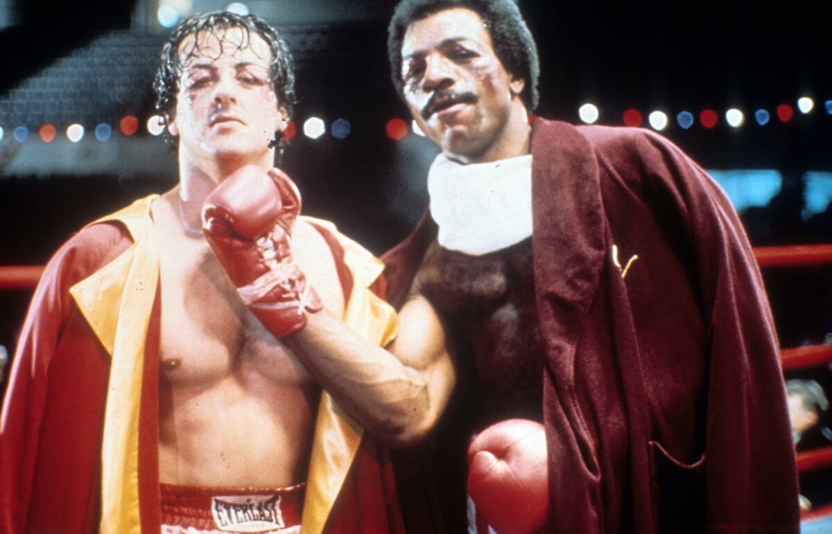 Sylvester Stallone as Rocky Balboa and Carl Weathers as Apollo Creed on set of "Rocky" in 1976.