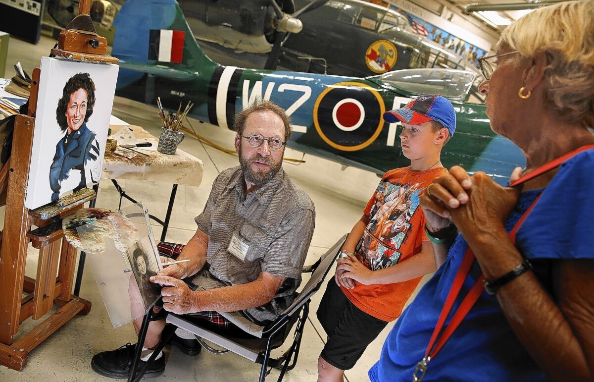 Portrait artist Chris Demarest pauses to talk with Palm Springs Air Museum visitors Lenore Crilly of Sierra Madre and grandson Ethan Jordan, 9, of Glendora.