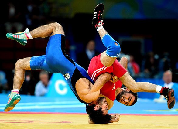 Muzad Ramazanov, of Macedonia, in blue, and Zalimkhan Huseynov, of Azerbaijan, get tangled during the 60-kg weight-class freestyle wrestling competition.