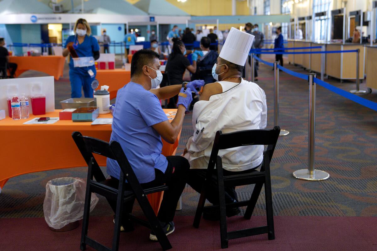 Ruben Quiocho, LVN de Sharp Healthcare administró la vacuna Pfizer COVID-19 a Sinu Pillai.