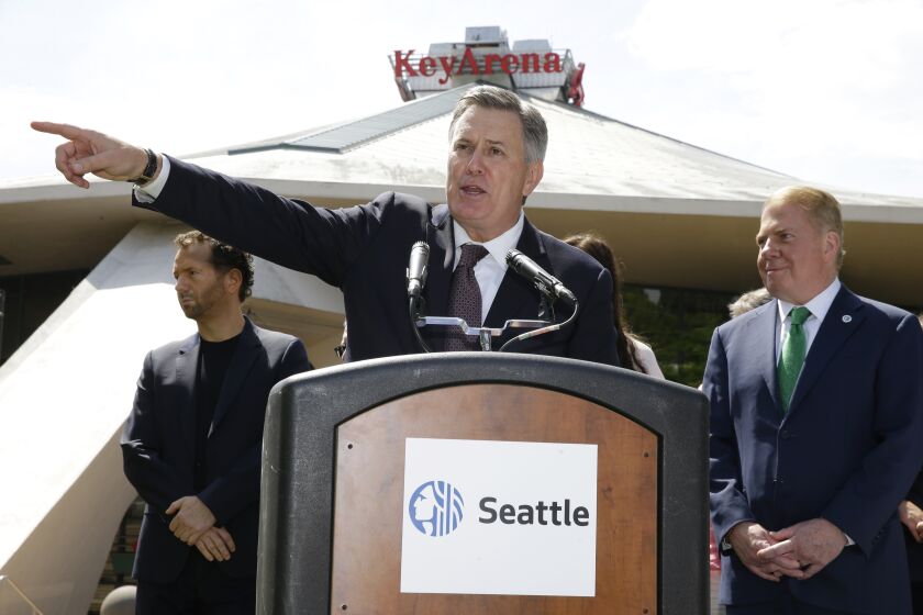 Tim Leiweke, CEO of the Oak View Group, center, speaks during a news conference as Seattle Mayor Ed Murray looks on at right on Wednesday, June 7, 2017, in front of KeyArena in Seattle. Murray said the city will enter into negotiations with the Oak View Group on a proposal for a privately-financed renovation of the city-owned KeyArena. Plans for the remodel would bring the building up to standards that could attract an NHL or NBA franchise once completed. (AP Photo/Ted S. Warren)