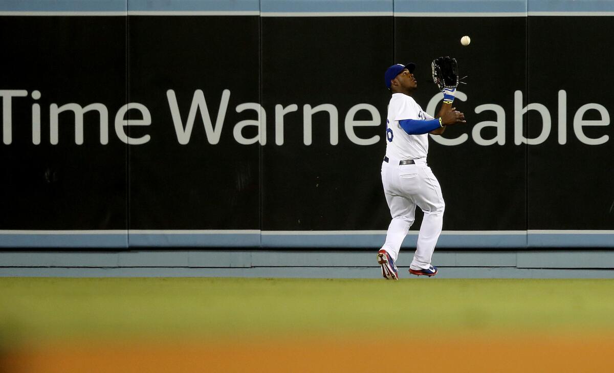 Dodger center fielder Yasiel Puig makes a catch in front of a Time Warner Cable advertisement on the outfield wall during a game against the Angels in 2014 at Dodger Stadium in Los Angeles.