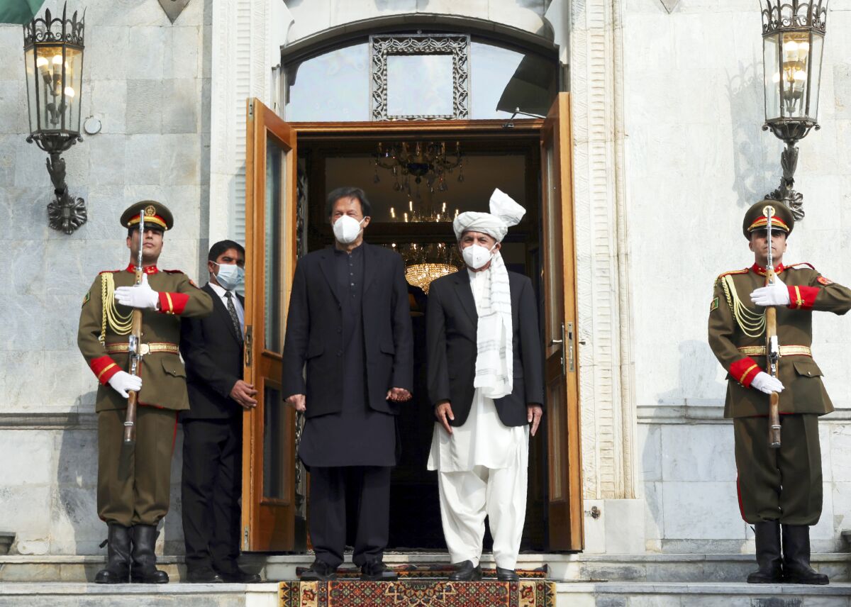 Pakistani Prime Minister Imran Khan stands in a doorway with Afghan President Ashraf Ghani