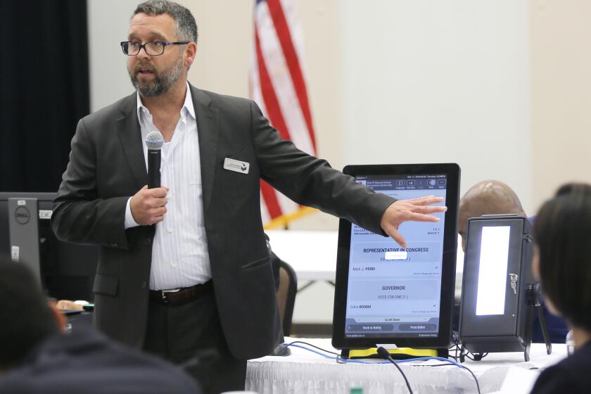 FILE - In this Thursday, Aug. 30, 2018 file photo, Eric Coomer from Dominion Voting demonstrates his company's touch screen tablet that includes a paper audit trail at the second meeting of Secretary of State Brian Kemp's Secure, Accessible & Fair Elections Commission in Grovetown, Ga. Eric Coomer, driven into hiding by death threats has filed a defamation lawsuit against President Donald Trump's campaign, two of its lawyers and some conservative media figures and outlets, Tuesday, Dec. 22, 2020. (Bob Andres/Atlanta Journal-Constitution via AP, File)