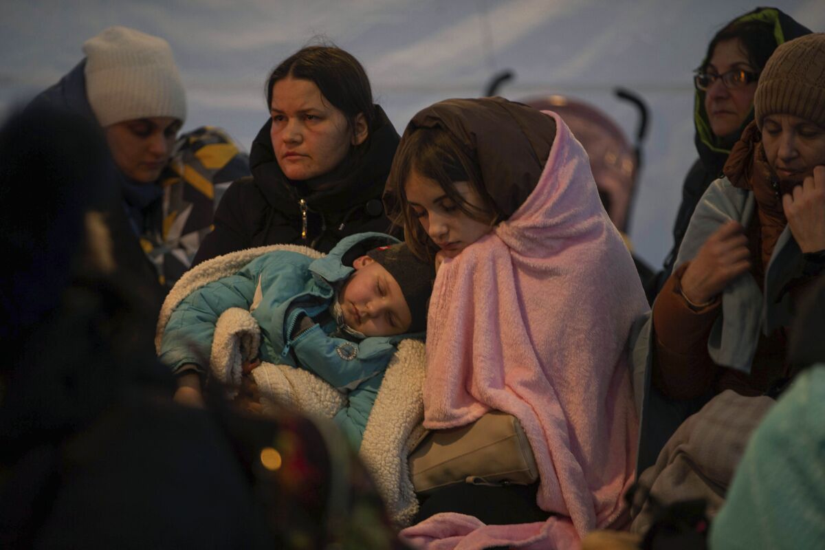 Refugees, mostly women with children, rest inside a tent after arriving at the border crossing, in Medyka, Poland on Sunday, March 6, 2022. (AP Photo/Visar Kryeziu)