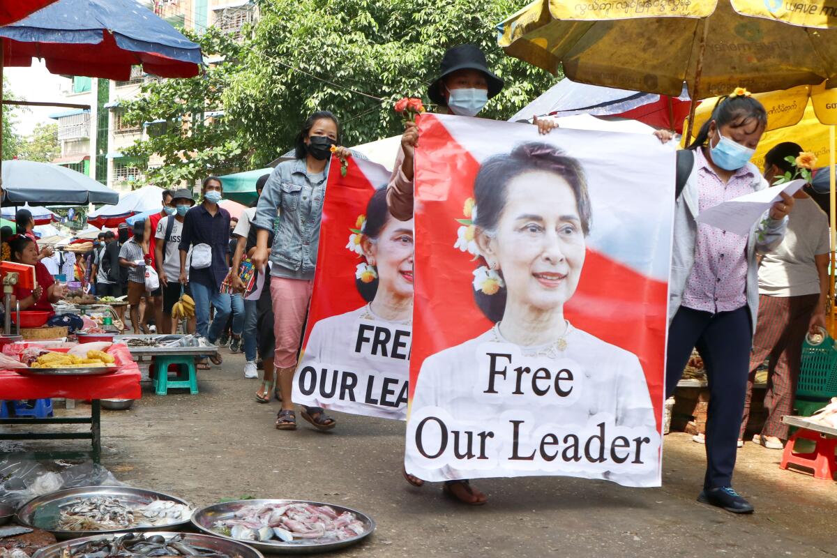 Protesters carry banners with Aung San Suu Kyi's picture and the text "Free Our Leader."