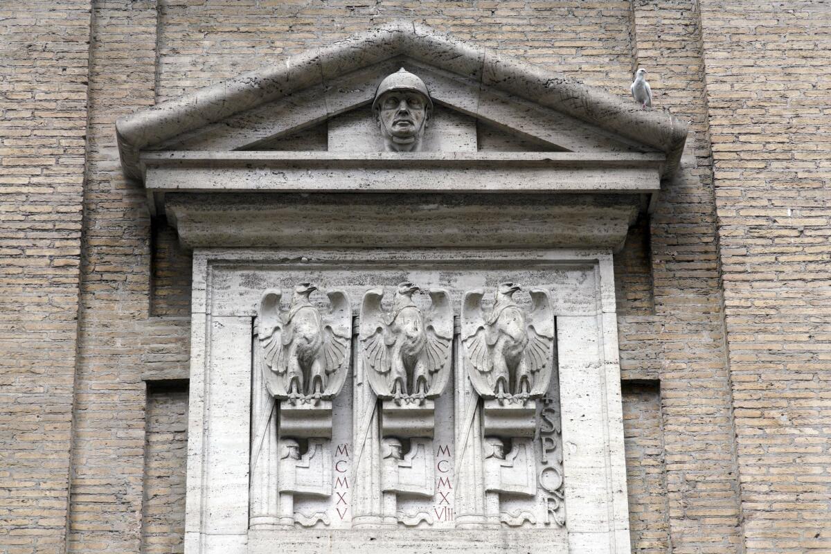 The stone face of a church showing eagles carved alongside bundles of rods tied around an axe