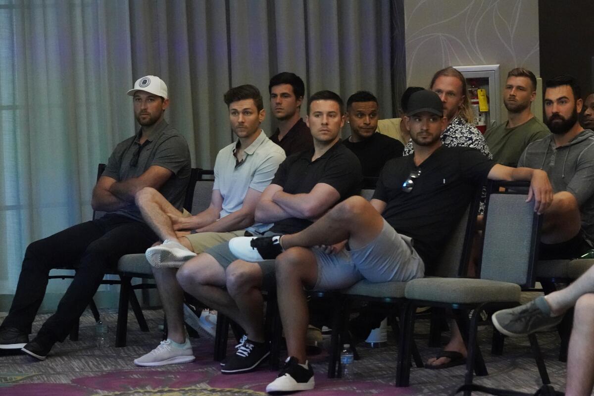 Baseball players listen during a news conference.