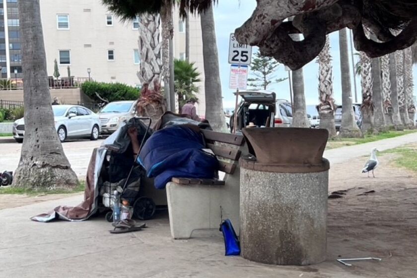 A homeless person sleeps on a bench at Girard Avenue and Coast Boulevard in La Jolla in October.