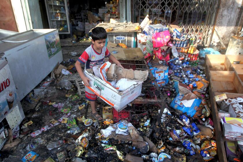 An Iraqi child helps his father (unseen) clean up his shop, which was destroyed the previous day in a car bomb attack in the Shiite-dominated district of Baghdad al-Jadida on Oct. 2, 2014.