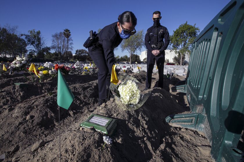 Westminster, CA - January 14: Rayah Alshilleh, left, flanked by brother Mahmoud places flowers at the grave of their father Hashem Ahmad Alshilleh at Westminster Memorial Park Mortuary on Thursday, Jan. 14, 2021 in Westminster, CA. (Irfan Khan / Los Angeles Times)