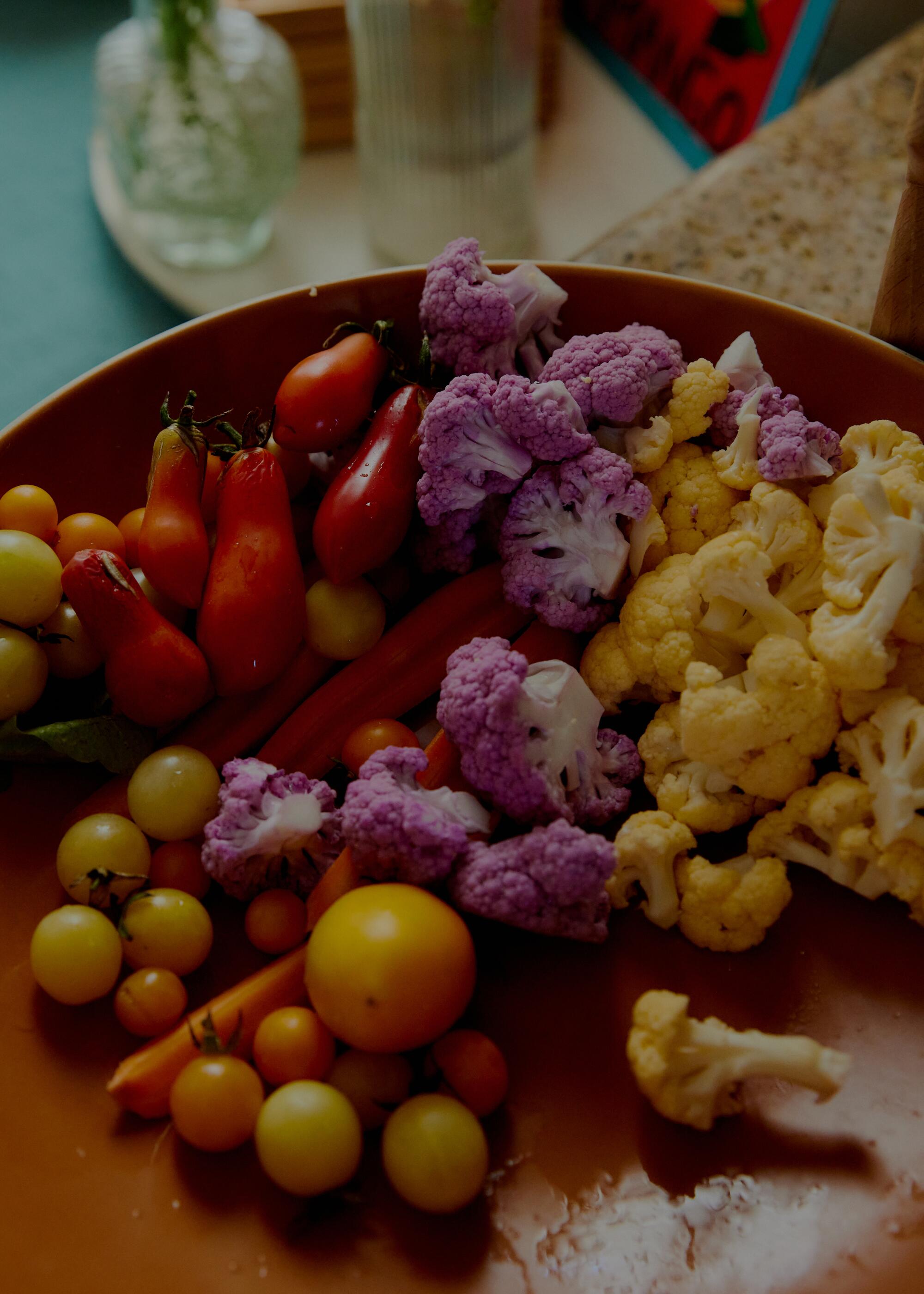 A bowl of farm fresh tomatoes, carrots, and cauliflower florets.