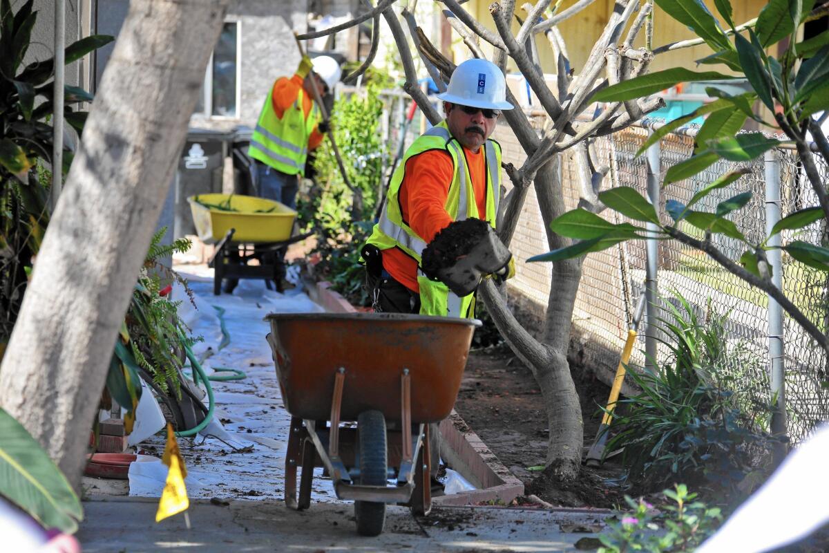 Work crews remove topsoil from yards in the 1200 block of South Indiana Street in Boyle Heights.