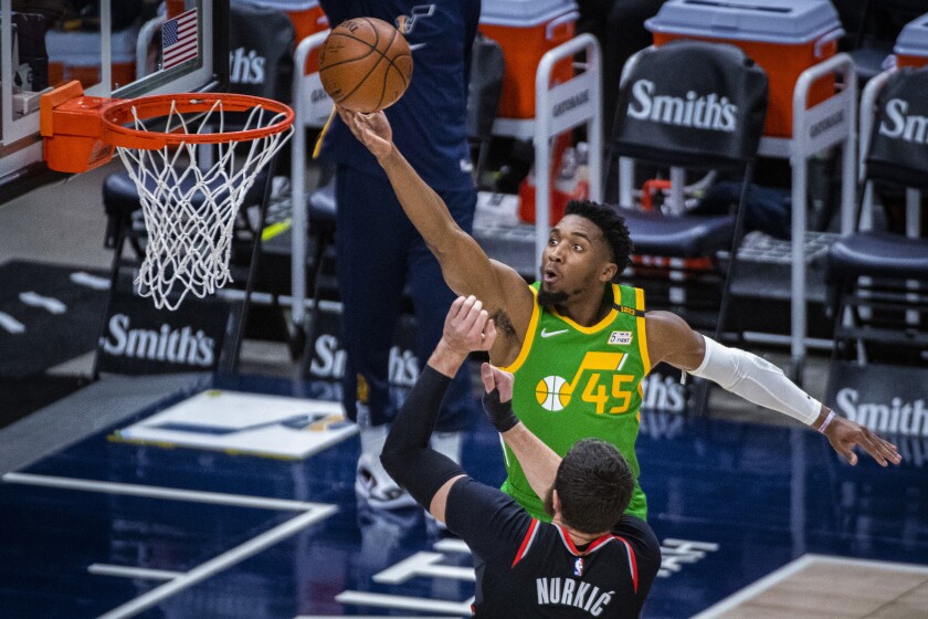 Utah Jazz guard Donovan Mitchell (45) lays the ball up while guarded by Portland Trail Blazers center Jusuf Nurkic (27) during the first half of an NBA basketball game Thursday, April 8, 2021, in Salt Lake City. (AP Photo/Isaac Hale)