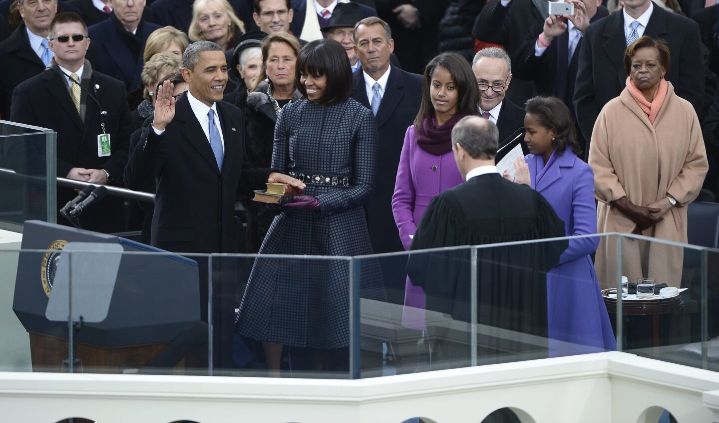 President Barack Obama places his hand on a bible held by Michelle Obama as he is ceremonially sworn in for a second term by Chief Justice John Roberts, right.