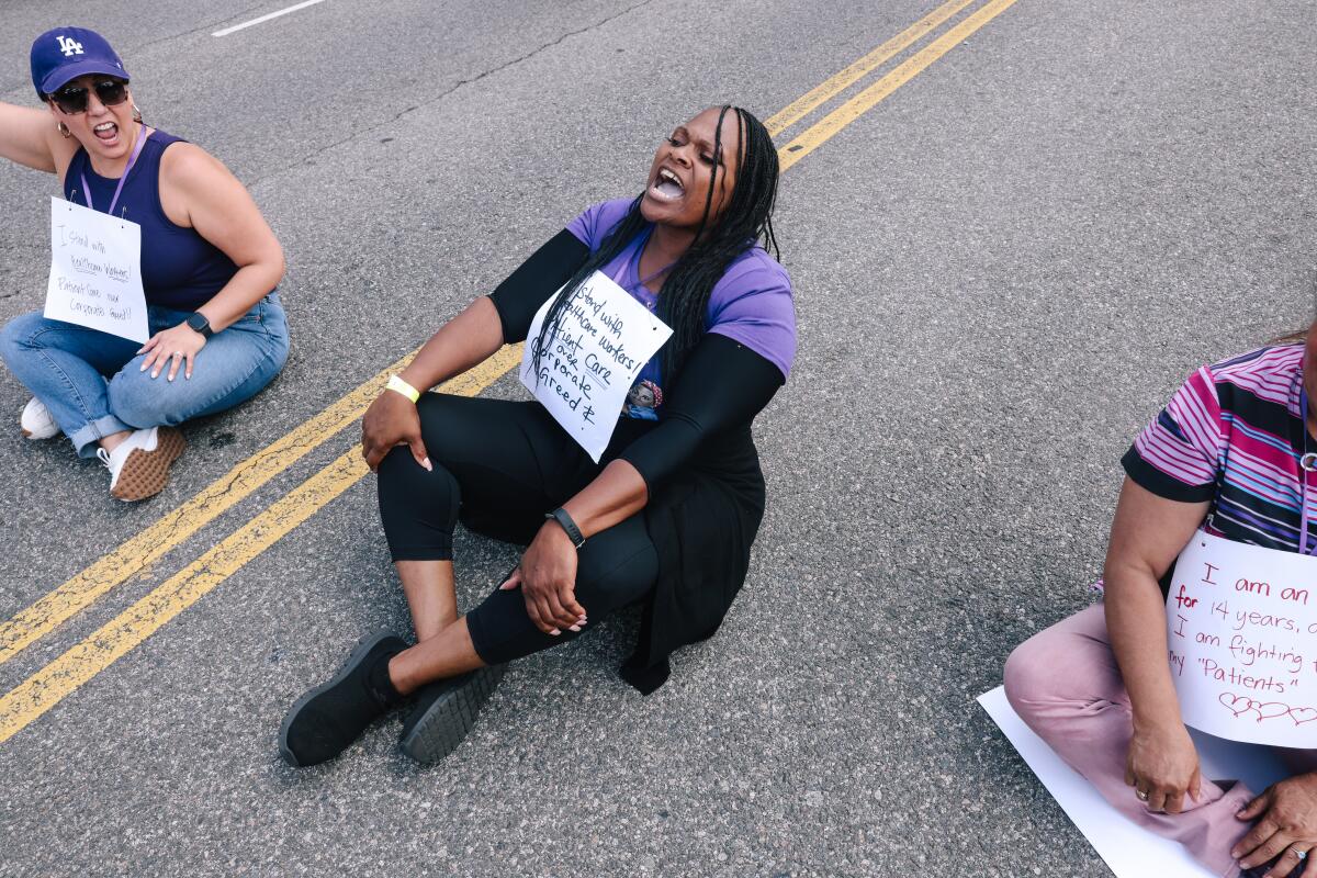 People wear signs and chant as they sit in the street.