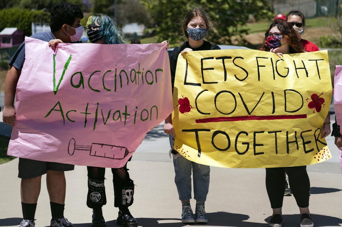 High school students hold vaccination signs at a school-based COVID-19 vaccination event