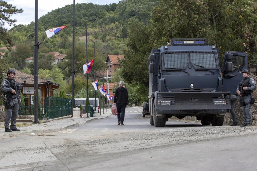 A local Serb man walks past Kosovo police officers securing the area around the Banjska monastery in the village of Banjska, Kosovo on Wednesday, Sept. 27, 2023. Police on Wednesday allowed media into the village of Banjska, where a daylong shootout between armed Serbs and Kosovar police on Sunday left one officer and three gunmen dead. (AP Photo/Visar Kryeziu)
