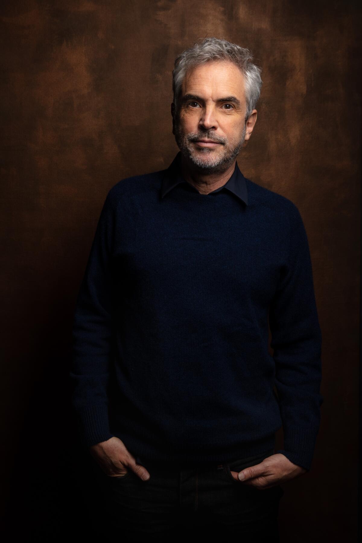A portrait of filmmaker Alfonso Cuarón standing with his hands in his pocket.
