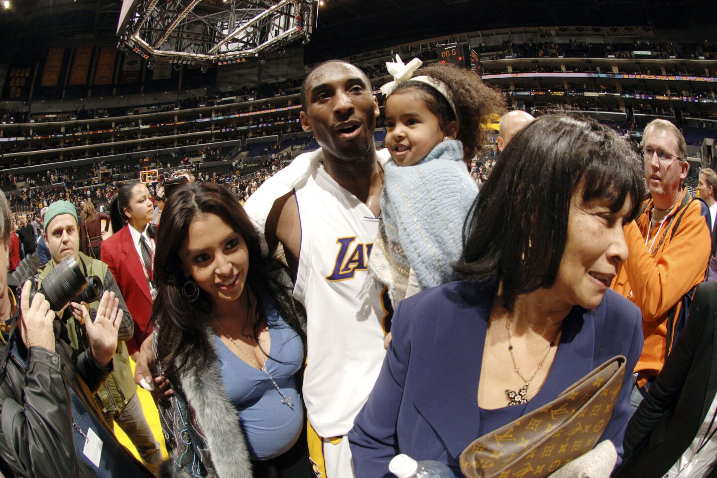 Among a crowd, Kobe Bryant walks off the court, carrying daughter Natalia, with wife Vanessa after scoring 81 points.