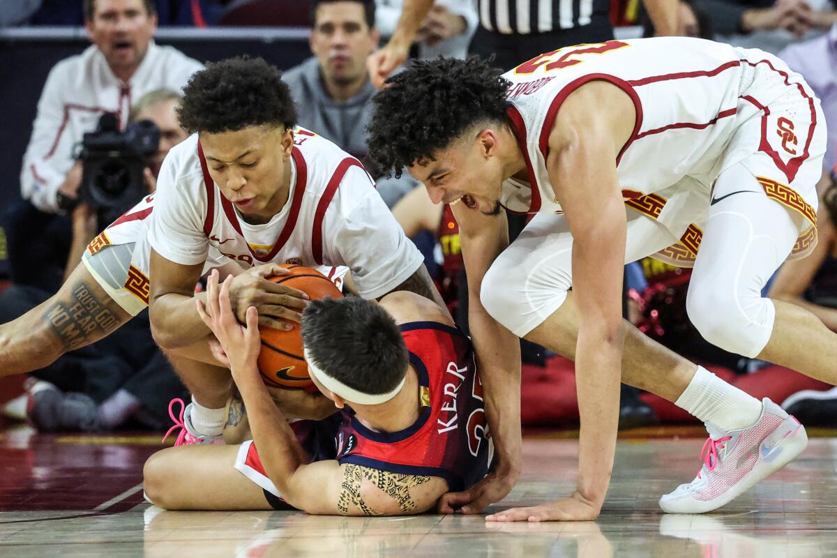 USC guard Boogie Ellis and forward Max Agbonkpolo wrestle for the ball with Arizona guard Kerr Kriisa.