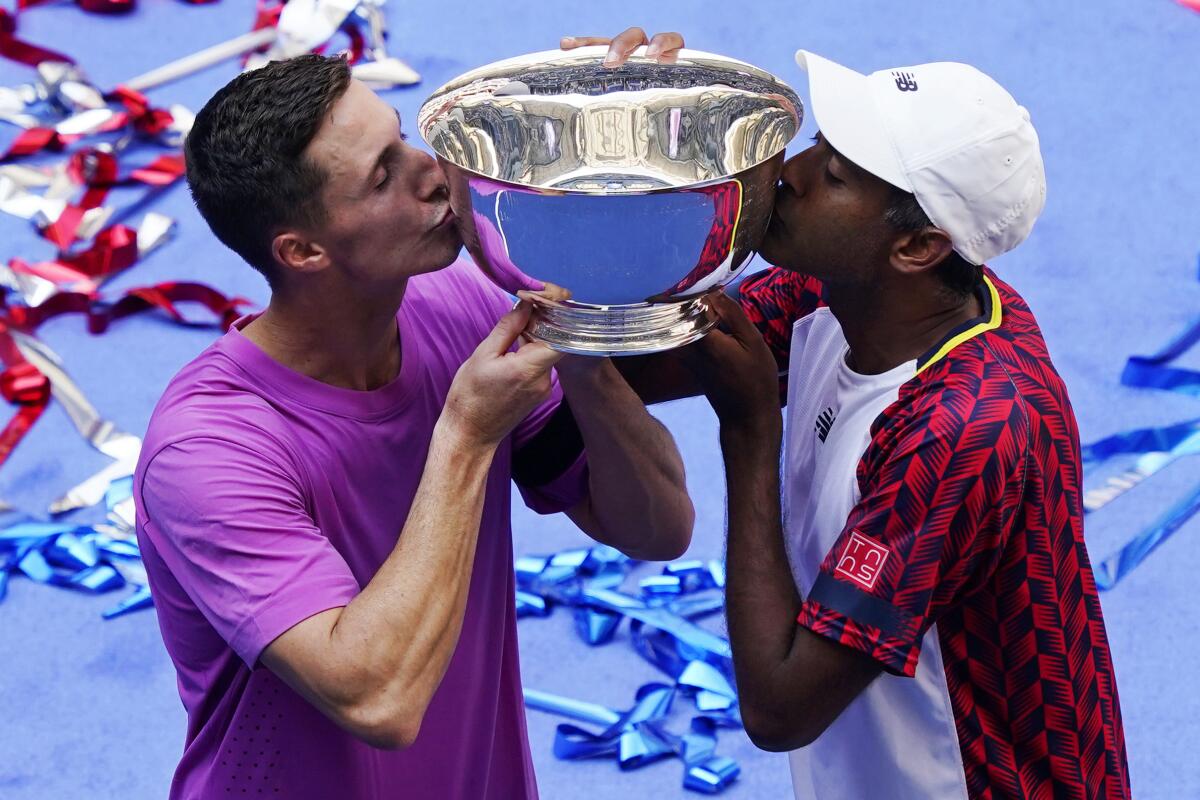 Rajeev Ram, of the United States, right, and Joe Salisbury, of Britain, kiss the trophy after defeating Wesley Koolhof, of the Netherlands, and Neal Skupski, of Britain, in the final of the men's doubles at the the U.S. Open tennis championships, Friday, Sept. 9, 2022, in New York. (AP Photo/Matt Rourke)