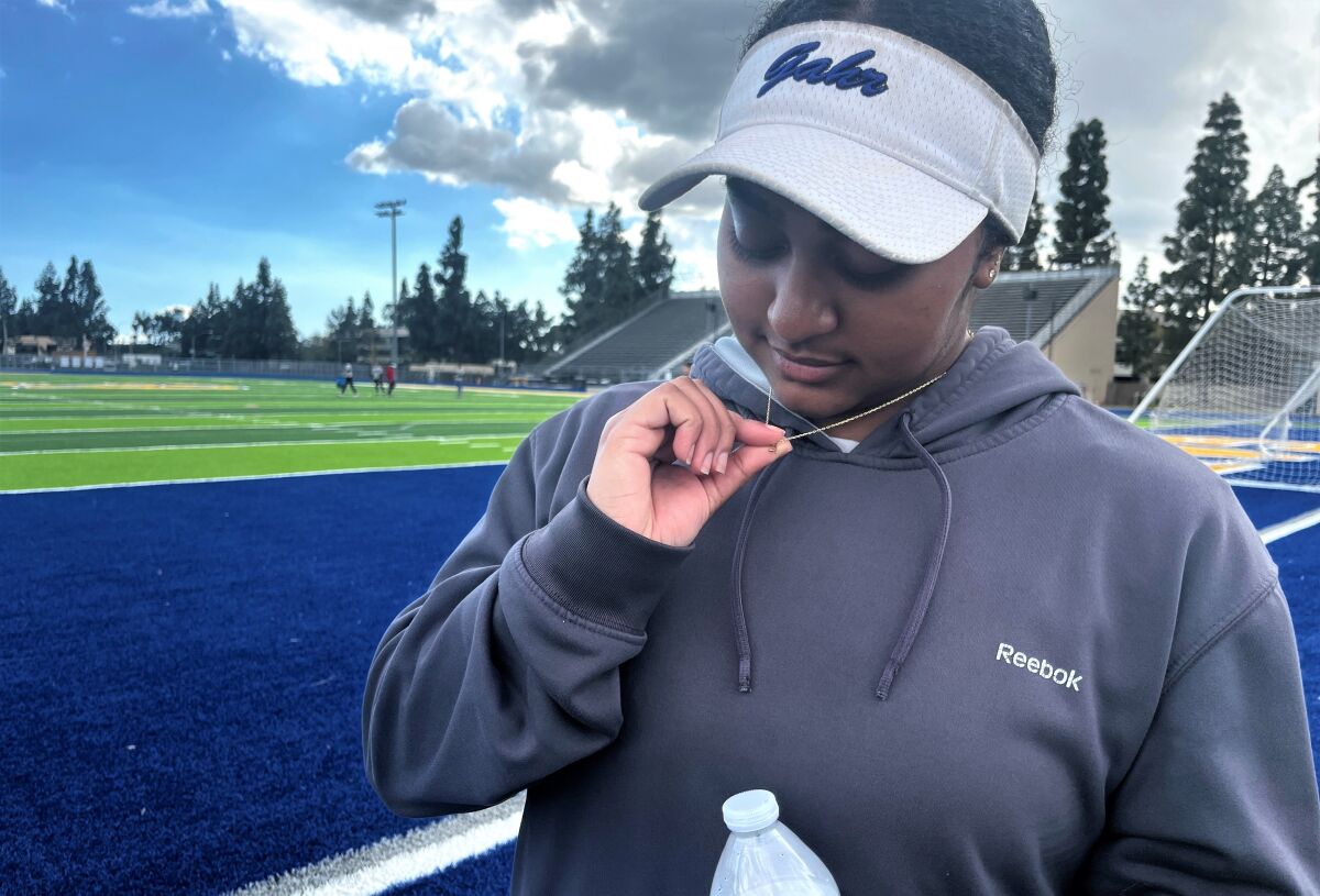 Gahr High softball players Amarie Allen checks out the pendant on her necklace that honors her late father.