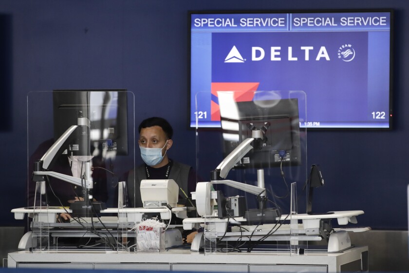 FILE - An agent works the counter at the Delta Air Lines terminal at the Los Angeles International Airport, Thursday, May 28, 2020, in Los Angeles. Delta Air Lines is reporting a $408 million loss for the final quarter of 2021, dragged down by a COVID-19 surge that rocked the airline in December, and the carrier expects to suffer one more quarterly loss before travel picks up in the spring and summer. (AP Photo/Marcio Jose Sanchez, File)