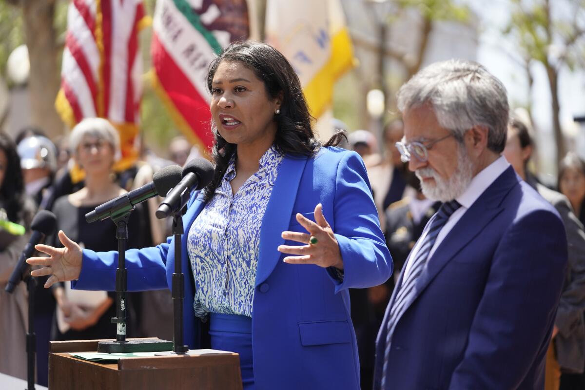 San Francisco Mayor London Breed, left, speaks at a lectern with rival Aaron Peskin, right