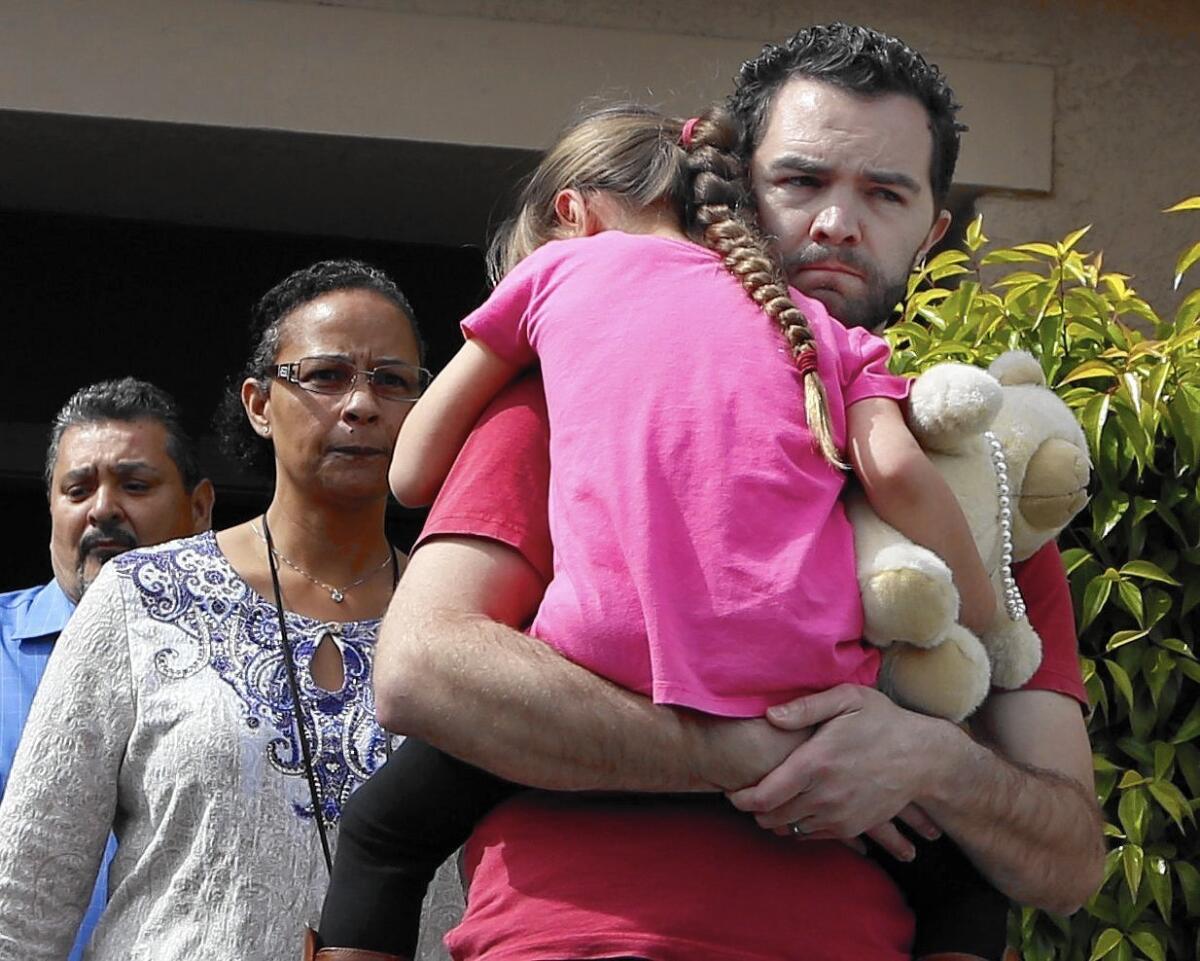 Rusty Page carries his foster daughter as they are escorted to a car.