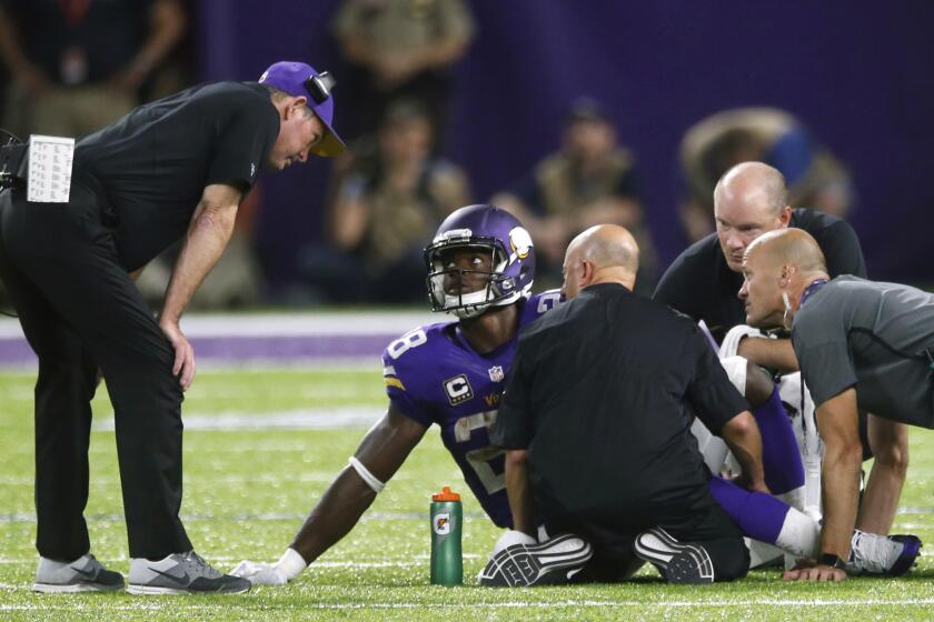 Minnesota Vikings running back Adrian Peterson talks with Coach Mike Zimmer, left, after getting injured against Green Bay.