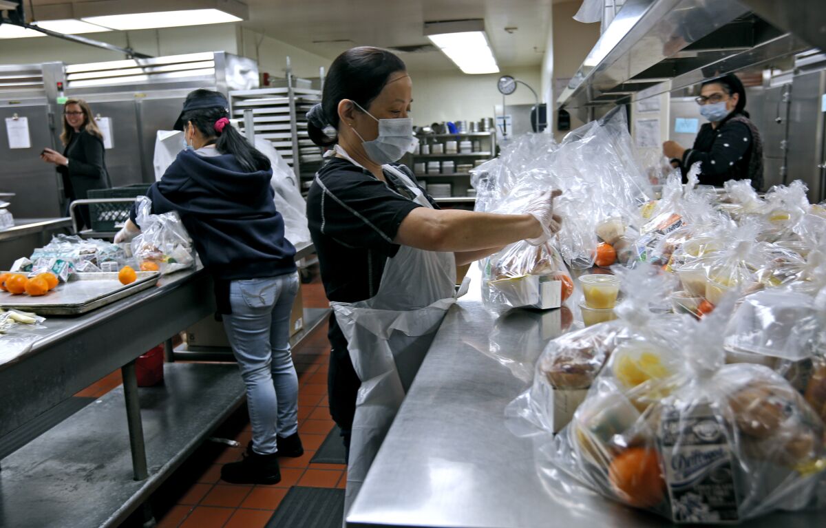 Cafeteria workers like Cielo Ramos, center, prepare bagged meals for students at Glendale High School for the Glendale Unified's grab-and-go drive-up meal service.