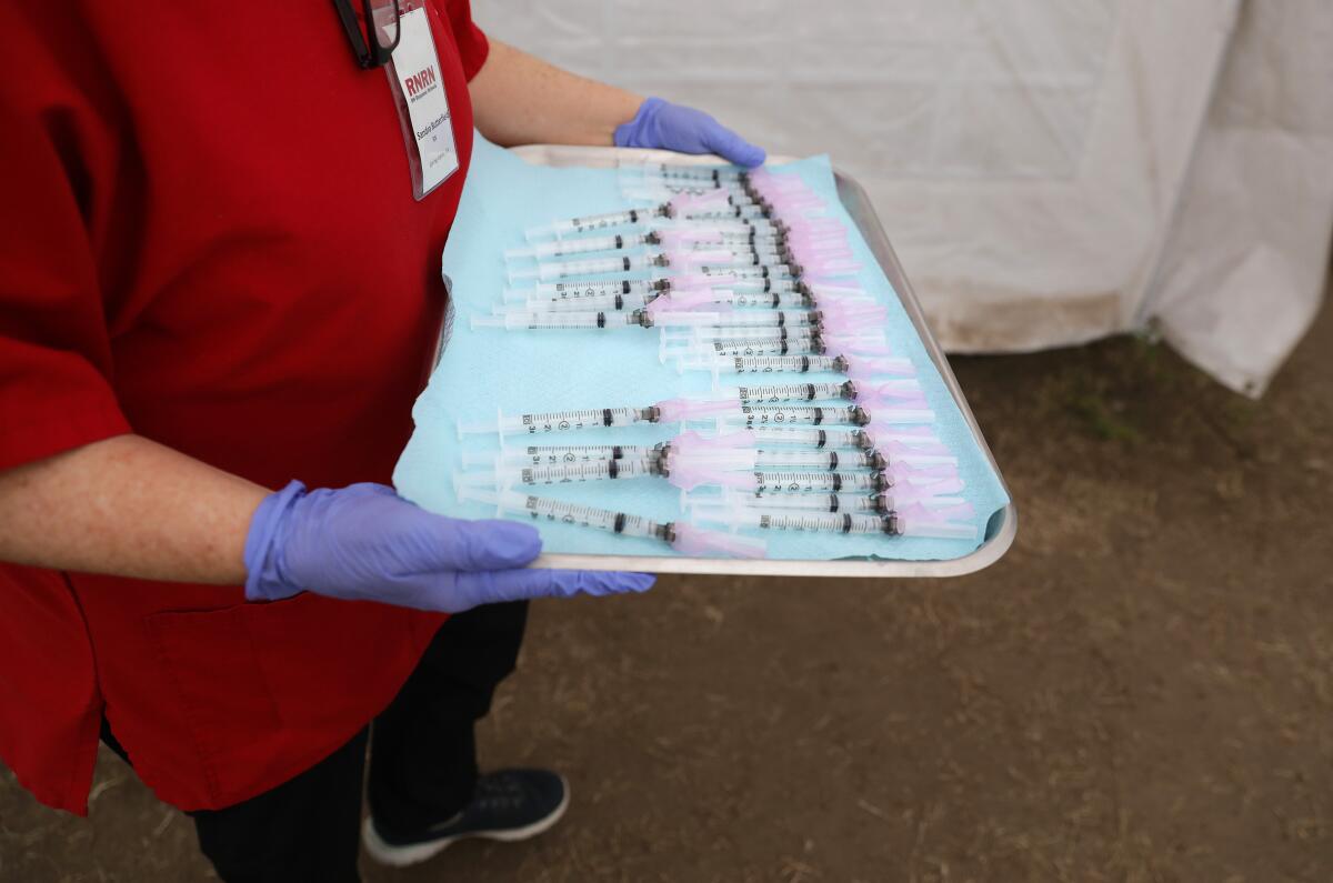 A nurse holds a tray of syringes
