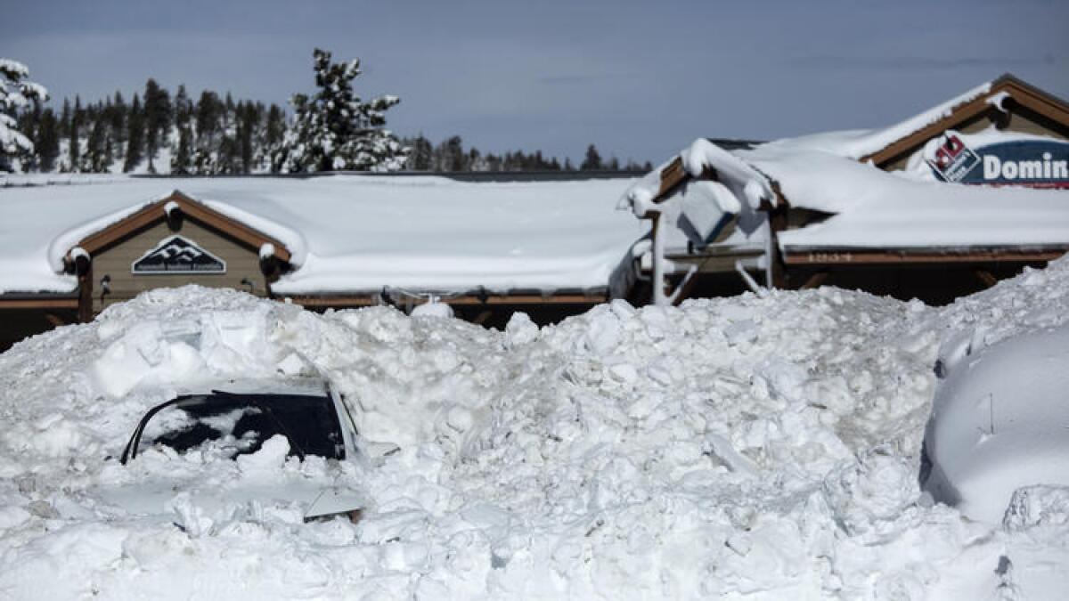 Snow covers vehicles in a parking lot in Mammoth Lakes.