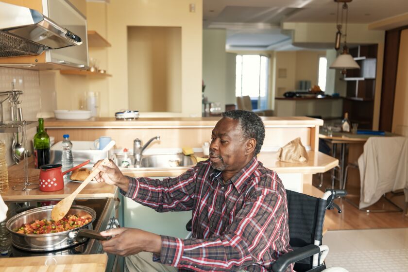 A man in a wheelchair prepares food on a stove.